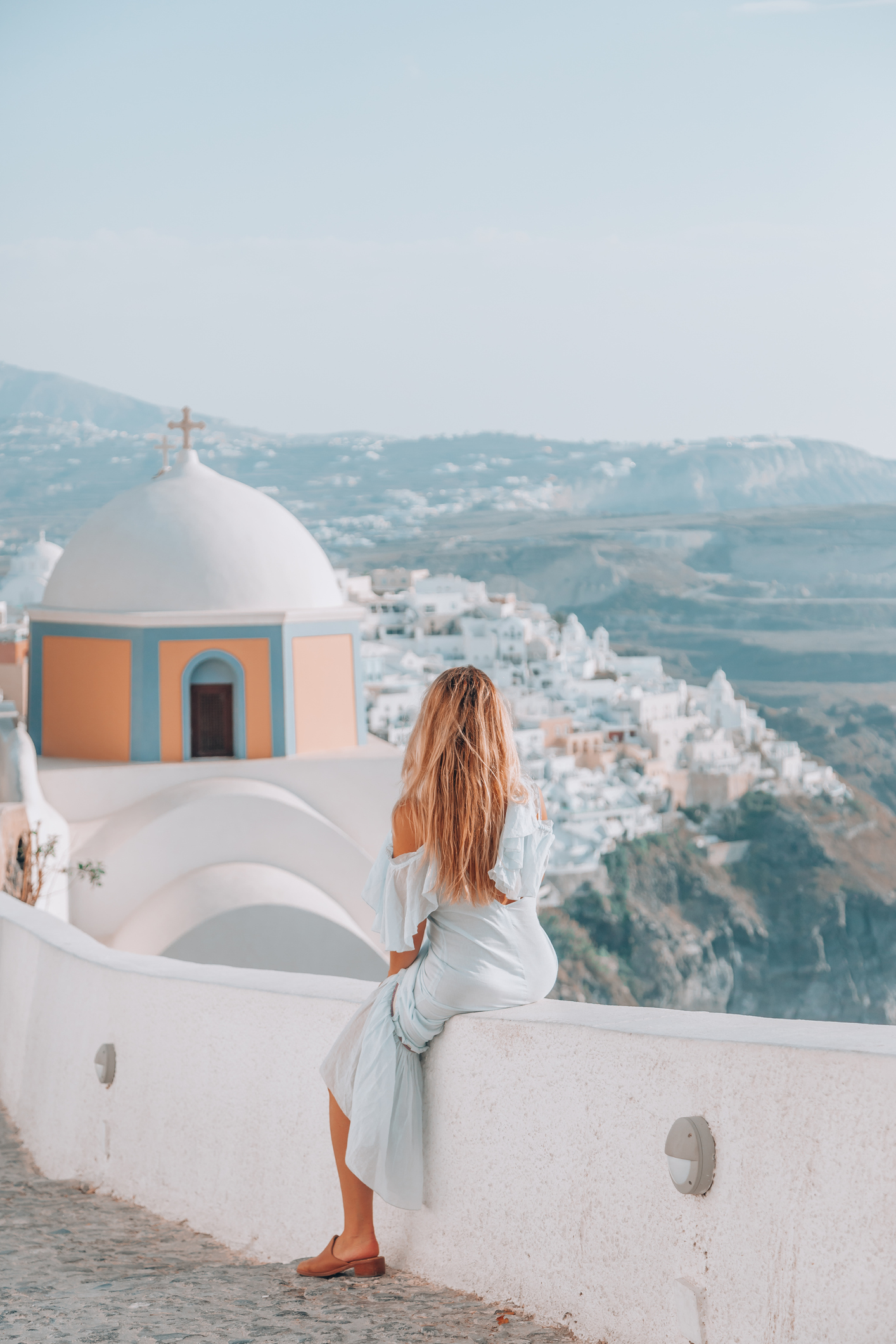 Young woman enjoys traveling and looking at view in Santorini, Greece
